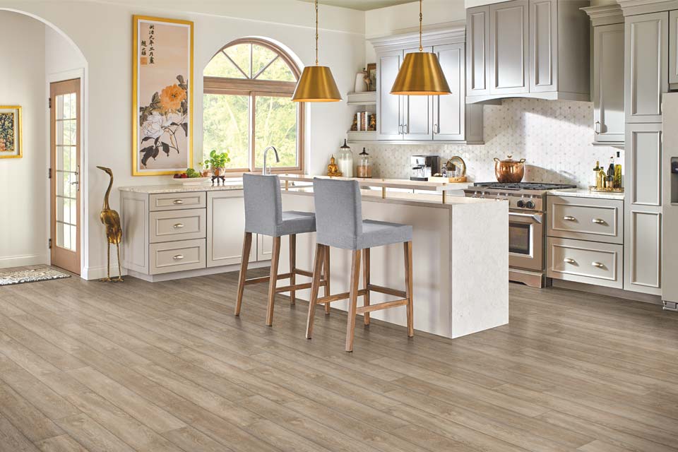 luxury vinyl flooring in kitchen with like grey cabinets and stone kitchen island with grey stools and mixed metal decor.